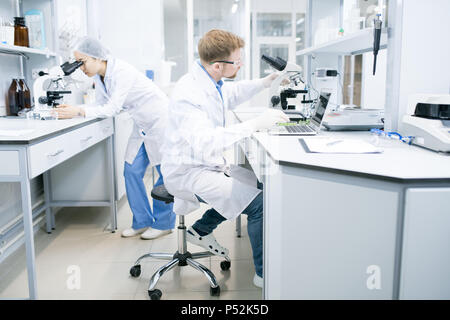 Scientist working with laptop and microscope Stock Photo