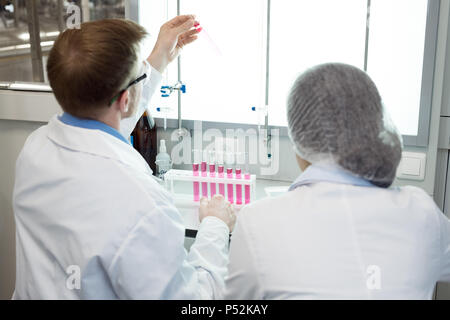 Microbiologists studying pink solution in test tube