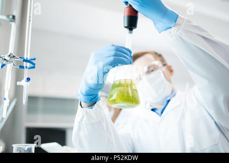 Male scientist taking probe of green liquid 