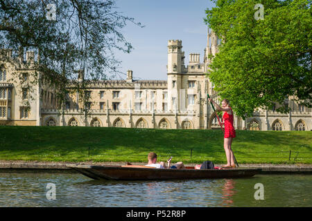 A young couple punting on the river Cam past St Johns College university on a sunny Summer afternoon, Cambridge, UK