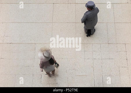 A view of two race goers on their way to Ascot races, taken from above on the concourse of Waterloo Station Stock Photo