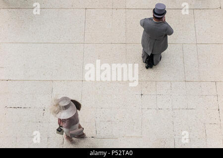 A view of two race goers on their way to Ascot races, taken from above on the concourse of Waterloo Station Stock Photo