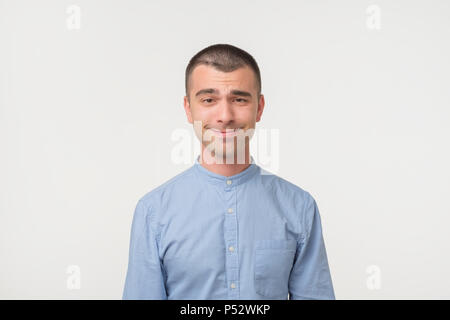 Handsome latino man shows surprised smile grimace or facial expression, isolated on white background. Making funny emotion on face Stock Photo
