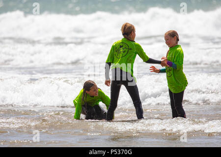 School children in wet suits playing in the surf before a surfing lesson at Whitsand Bay, Cornwall on a hot summers day Stock Photo