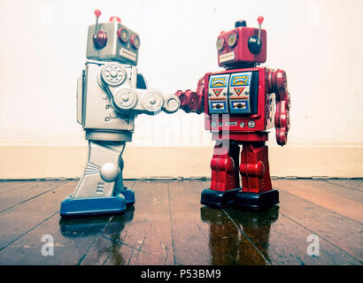 two vintage robot shake hands on a old wooden floor  toned image Stock Photo