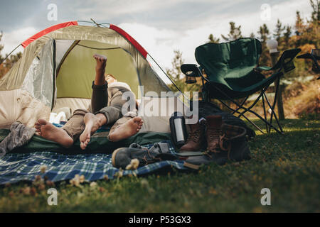 Romantic young couple lying inside a tent at campsite. Man and woman in love in a tent. Stock Photo