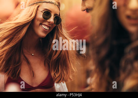 Young girl in hippie style at music festival. Beautiful young woman at music festival with friends. Stock Photo