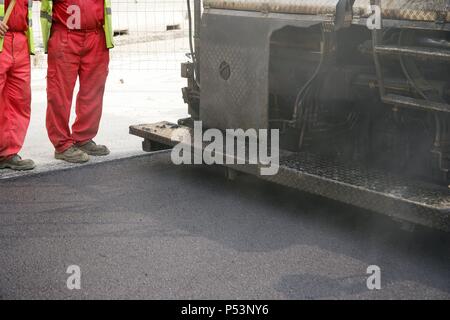 Paving work. Asphalt paving machine. New asphalt surface on the carriageway. Barcelona. Spain. Stock Photo