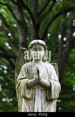 A statue of a praying angel with a broken wing sitting in the grounds of saughton cemetery in Edinburgh Stock Photo
