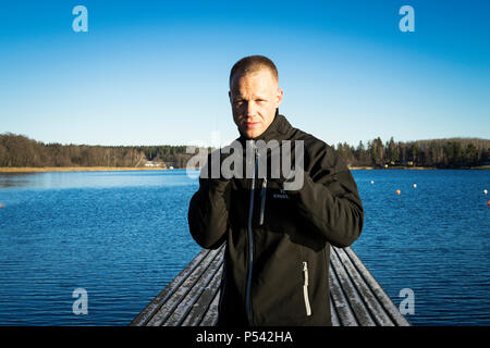 Portrait of male caucasian middle age boxer man outside in nature at lake in Sweden. Nice sunny winter day with blue sky. Wearing black sport jacket. Stock Photo