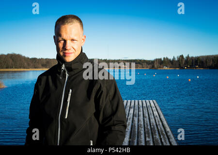 Portrait of male caucasian middle age boxer man outside in nature at lake in Sweden. Nice sunny winter day with blue sky. Wearing black sport jacket. Stock Photo