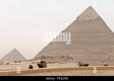 Horse drawn carriages carry tourists to the Pyramid of Khafre (Chephren), the second-tallest of the pyramids at Giza, and tomb of Khafre. Stock Photo