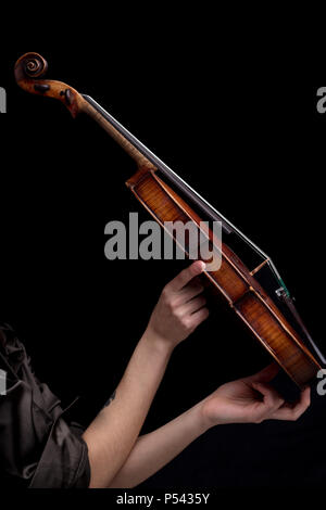 baroque violin held by woman's hand on a black background Stock Photo