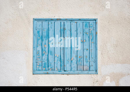 Cyprus, Larnaca. Blue wooden, peeled window, shutters on pink wall. Facade of old stone building, closeup. Stock Photo