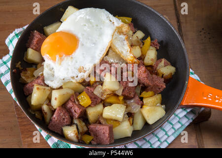 Freshly cooked Corned beef hash with a fried egg served in the pan. Stock Photo