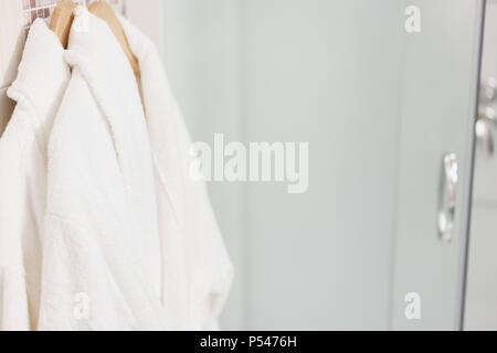 Clean white towel and bathrobe on a hanger prepared to use. Bathroom Inside rooms of a apartment or hotel. Stock Photo
