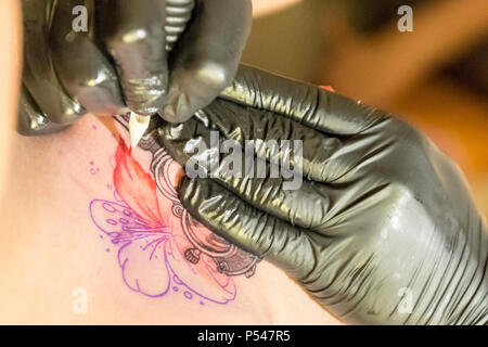 tattooer make a tattoo in the skin of a woman Stock Photo
