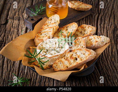 Baked cheese Camembert with rosemary and honey. Tasty food. Stock Photo