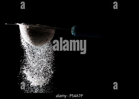 Flour sifting on a black background. White powder sift isolated on black background. Copy space Stock Photo