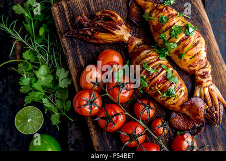 Korean BBQ squid calamary and ingredients on dark background. Traditional korean dish - grilled squid stuffed with onion and tomatoes. Top view. Stock Photo