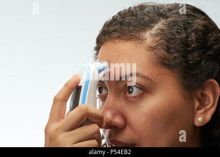 Measure temperature in forehead of young woman isolated on white background Stock Photo