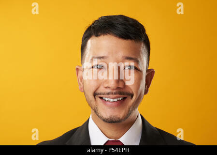 Happy smiling asian business man headshot portrait isolated on yellow background Stock Photo