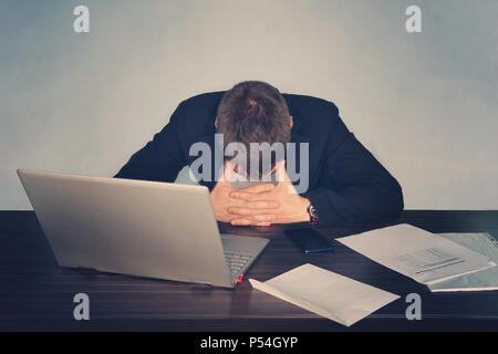 Exhausted tired businessman working on laptop at office, massaging temporal area, holding glasses, feeling fatigue discomfort, eye strain after long w Stock Photo