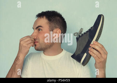 A man pinches his nostrils closed over the odor given off from the athletic shoe he is holding. Stock Photo