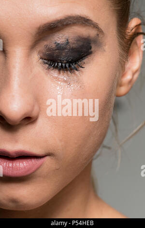 Sad crying girl eyes closed with smeared make-up close-up shot Stock Photo