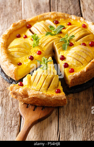 Sliced apple pie with cranberries and custard is decorated with mint close-up on the table. vertical Stock Photo