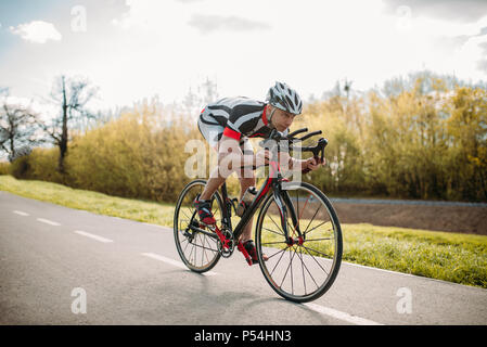 Male cyclist in helmet and sportswear rides on bicycle, front view. Workout on bike path, cycling Stock Photo