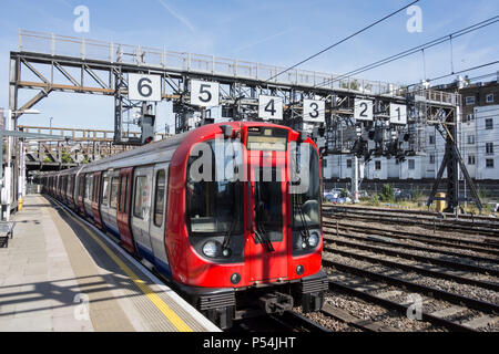 A Hammersmith and City Line Circle Line train passing under the Royal Oak signaling gantry on leaving Paddington Station, London, UK Stock Photo