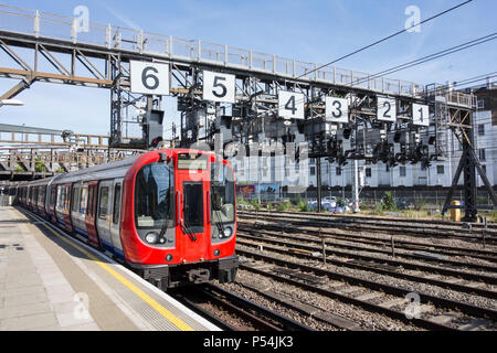 A Hammersmith and City Line Circle Line train passing under the Royal Oak signaling gantry on leaving Paddington Station, London, UK Stock Photo