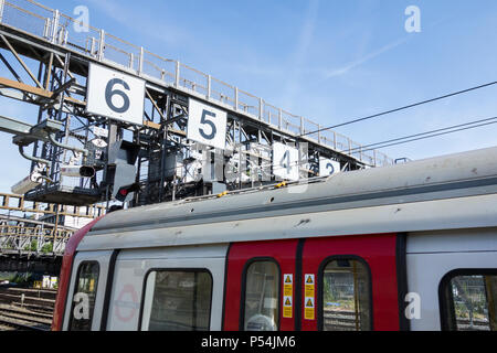 A Hammersmith and City Line Circle Line train approaching the Royal Oak signalling gantry on approach to Paddington Station, London, UK Stock Photo