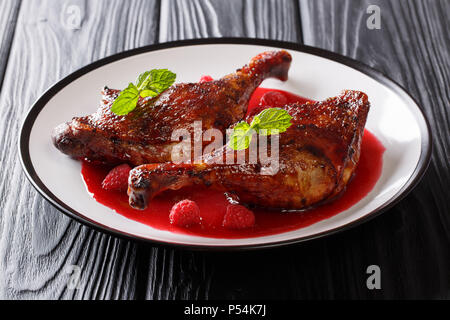 beautiful natural food: fried duck legs served with fresh raspberry sauce and mint closeup on a plate on the table. horizontal Stock Photo