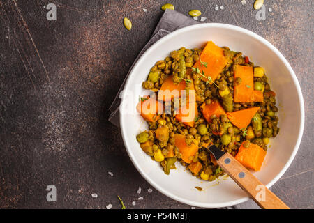 Lentil with pumpkin ragout in a white bowl on a dark background. Healthy vegan food concept. Stock Photo