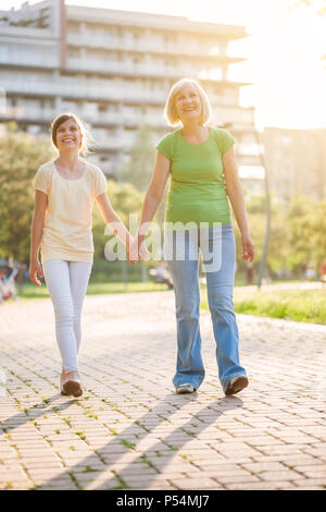 Grandmother and granddaughter are walking in park in summer. Stock Photo
