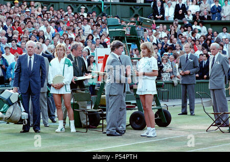 Winner Steffi Graf pictured right and Martina Navratilova, left holding her runners up plate. Steffi is talking with Alan Mills, Wimbledon Referee.  Steffi Graf beat current 6 times defending champion Martina Navratilova, to win the Wimbledon Ladies Singles Final on 2nd July 1988.    After Graf took a 5-3 lead in the first set, Navratilova won six straight games allowing her to win the first set and take a 2-0 lead in the second set. Graf then came back winning 12 of the next 13 games and the match.  Steffi Graf's first of 7 Wimbledon singles title wins. 1988, 1989, 1991, 1992, 1993, 1995, 199 Stock Photo