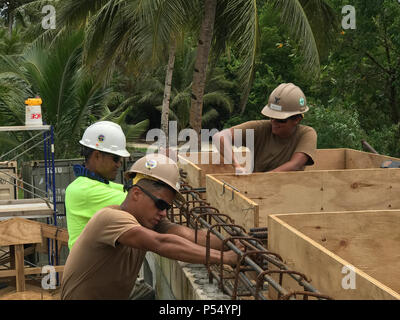 KOSRAE, Federated States of Micronesia (May 9, 2017) From the left, Local construction apprentice Mac George, Steelworker 3rd Class Timothy Vincent, from Minneapolis, Minnesota, and Construction Electrician 2nd Class Daniela Acevedo, from Crystal Lake, Illinois, tie in 90 degree rebar to a bond beam for the Naval Mobile Construction Battalion (NMCB) 1 Walung Health Clinic project in Kosrae, Federated States of Micronesia, May 11, 2017. NMCB 1 is forward deployed to execute construction, humanitarian and foreign assistance, special operations combat service support, and theater security coopera Stock Photo