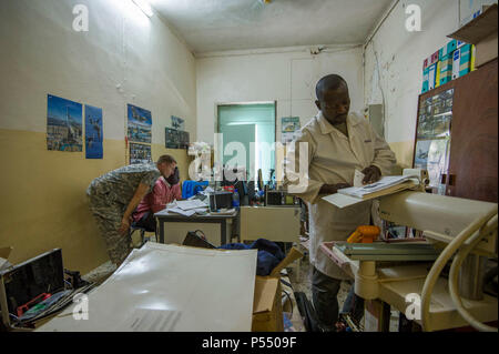 Onesime Kaoueye, chief biomedical technician, and U.S. Army Reserve Chief Warrant Officer 2 Doug Sires, a health services maintenance technician, conduct research while Chadian Lt. Djenaissem Bekoutou, a biomedical technician, reads a manual during Medical Readiness Training Exercise 17-3 at the Military Teaching Hospital in N'Djamena, Chad, May 10. The partnered medical equipment technicians will perform diagnostic tests and repair nonfunctional medical equipment. The mutually beneficial exercise offers opportunities for the partnered militaries to share best practices and improve medical tre Stock Photo