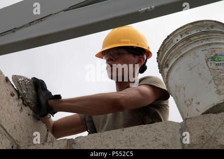 U.S. Army Spc. Yonik Perez, with the 485th Engineer Company, based out of Arlington Heights, Illinois, spreads cement on the top of a wall while building a new clinic in Double Headed Cabbage, Belize, May 10, 2017 Soldiers from the 485th are building a new health clinic in the village as a part of Beyond the Horizon 2017, a U.S. Southern Command-sponsored, Army South-led exercise designed to provide humanitarian and engineering services to communities in need, demonstrating U.S. support for Belize. Stock Photo