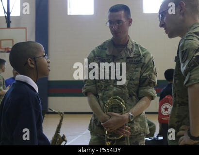 Joshua, a 6th-grader at Snelson-Golden Middle School, talks to Staff Sgt. David Oexmann and Spc. Nathan Gallaway, trombone players with the 3rd Infantry Division band. after the bands perfomance at the school. Students learn about the Army band from the Soldiers and are encouraged to pursue music. Stock Photo