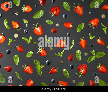 Flat lay view on fruit pattern with strawberries, blueberries and mint leaves on a black background. Stock Photo