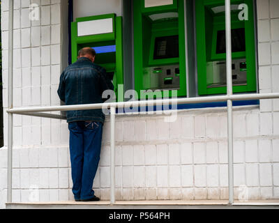Old Man using his credit card in an atm for cash withdrawal. Old man making internet purchases and using electronic technology concept Stock Photo