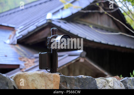 Surveillance camera on stone wall in front of traditional Japanese wooden building Stock Photo