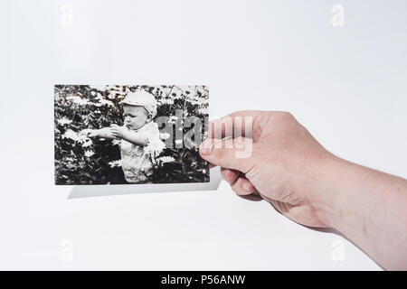 Old paper photo in mans hands. Abstract photo of childhood. Stock Photo