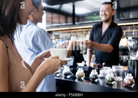 Young woman holding a white cup of coffee next to her partner Stock Photo