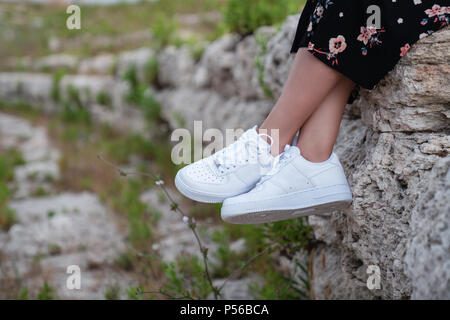 Female sneakers. White female shoes on feet. Sneakers closeup Stock Photo