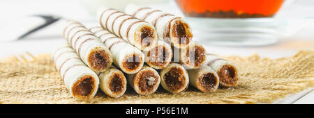 Striped wafer rolls, delicious chocolate snack on white wooden table Stock Photo