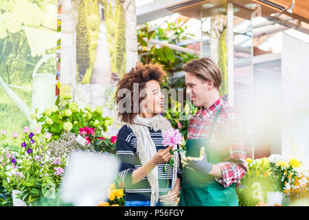Cheerful female customer buying flowers at the advice of a helpful vendor Stock Photo